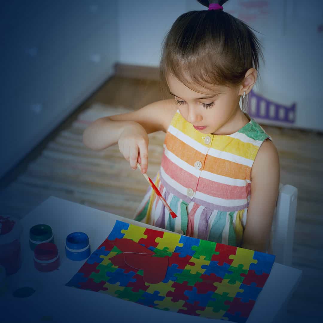 κοριτσάκι με αυτισμό ζωγραφίζει το παζλ του αυτισμού με χρώματα